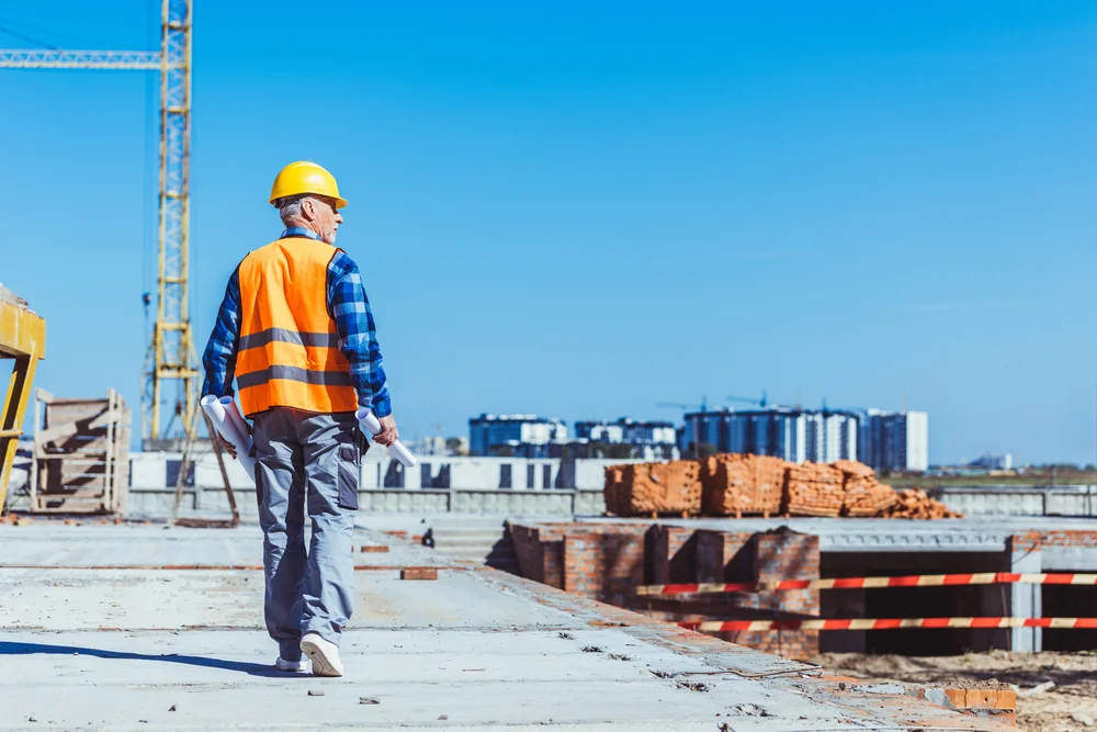 Bauleiter betrachtet Baupläne auf der Baustelle